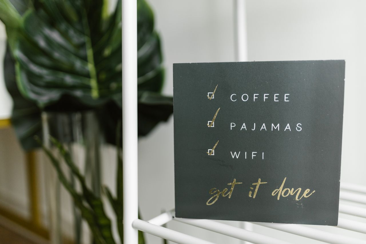 Close-up of a motivational checklist sign with a modern design featuring coffee, pajamas, and wifi.